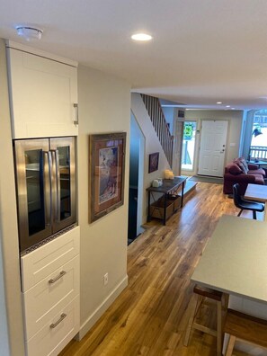 A modern kitchen with stainless steel appliances, a dining area with a wooden table and chairs, and a staircase leading to another level. - BEST LOCATION ON THE MOUNTAIN! Thunder Ridge 3 BR Ski in/Out Condo. Sleeps 8. (Fernie)