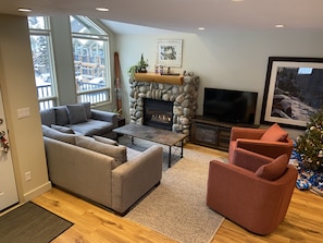 A living room with a stone fireplace, a large sofa, a coffee table, and a television. - BEST LOCATION ON THE MOUNTAIN! Thunder Ridge 3 BR Ski in/Out Condo. Sleeps 8. (Fernie)
