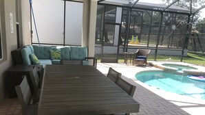 Un patio exterior con una mesa y sillas de madera, un sofá azul y una piscina.