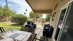 An outdoor patio with a glass-top table and wicker furniture, surrounded by a covered area with a view of the backyard. - Sun, Fun, Golf, Swim, Relax in Your Own Resort Home. (Glendale)