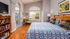 A bedroom with a bed, a bookshelf, a ceiling fan, a window with blinds, and a painting on the wall. - Sun, Fun, Golf, Swim, Relax in Your Own Resort Home. (Glendale)