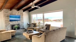 Un salon doté d’une cheminée en pierre, d’une grande fenêtre offrant une belle vue et d’un ventilateur de plafond.