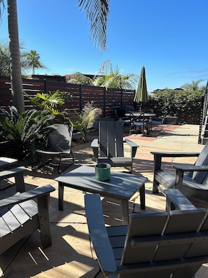 Relax in a serene outdoor space with comfortable seating, lush greenery, and a shaded area.