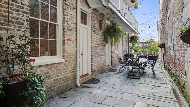 A narrow alley with a brick building, a white door, and a table with chairs. - Luxury 2-Story Condo / Prime Location (New Orleans)