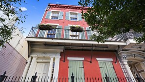 A red building with green shutters, a white door, and a black iron fence. - Luxury 2-Story Condo / Prime Location (New Orleans)