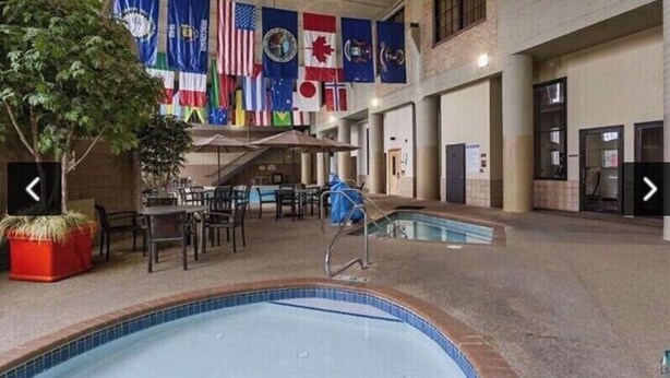 An indoor swimming pool area with multiple flags, a pool, and seating arrangements.