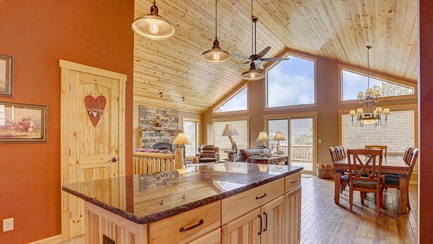 A spacious kitchen with wooden cabinets, a granite countertop, and a dining area with a table and chairs. - Luxury Home, Breathtaking Views, Hot Tub, Colorado Rocky Mountains (Estes Park)