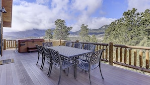 A deck with a table and chairs, a hot tub, and a view of mountains and trees. - Luxury Home, Breathtaking Views, Hot Tub, Colorado Rocky Mountains (Estes Park)