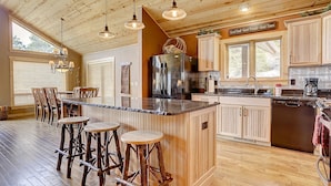 A spacious kitchen with wooden cabinets, a large island with stools, and a stainless steel refrigerator. - Luxury Home, Breathtaking Views, Hot Tub, Colorado Rocky Mountains (Estes Park)