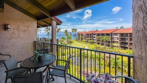 A balcony with a table and chairs, overlooking a golf course and hotel buildings.