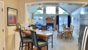 Un espace repas comprenant une table et des chaises en bois, une cheminée et une vue sur l’extérieur.