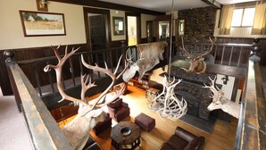 Ein Zimmer mit Steinwand, Holzmöbeln und aufgehängten Tierköpfen.