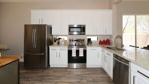 Una cocina moderna con armarios blancos, electrodomésticos de acero inoxidable y encimera de madera.