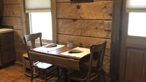 A wooden dining table with chairs, a window with blinds, a door, and a wall-mounted sign. - Couples Getaway with a Great Mountain View (Blue Ridge)