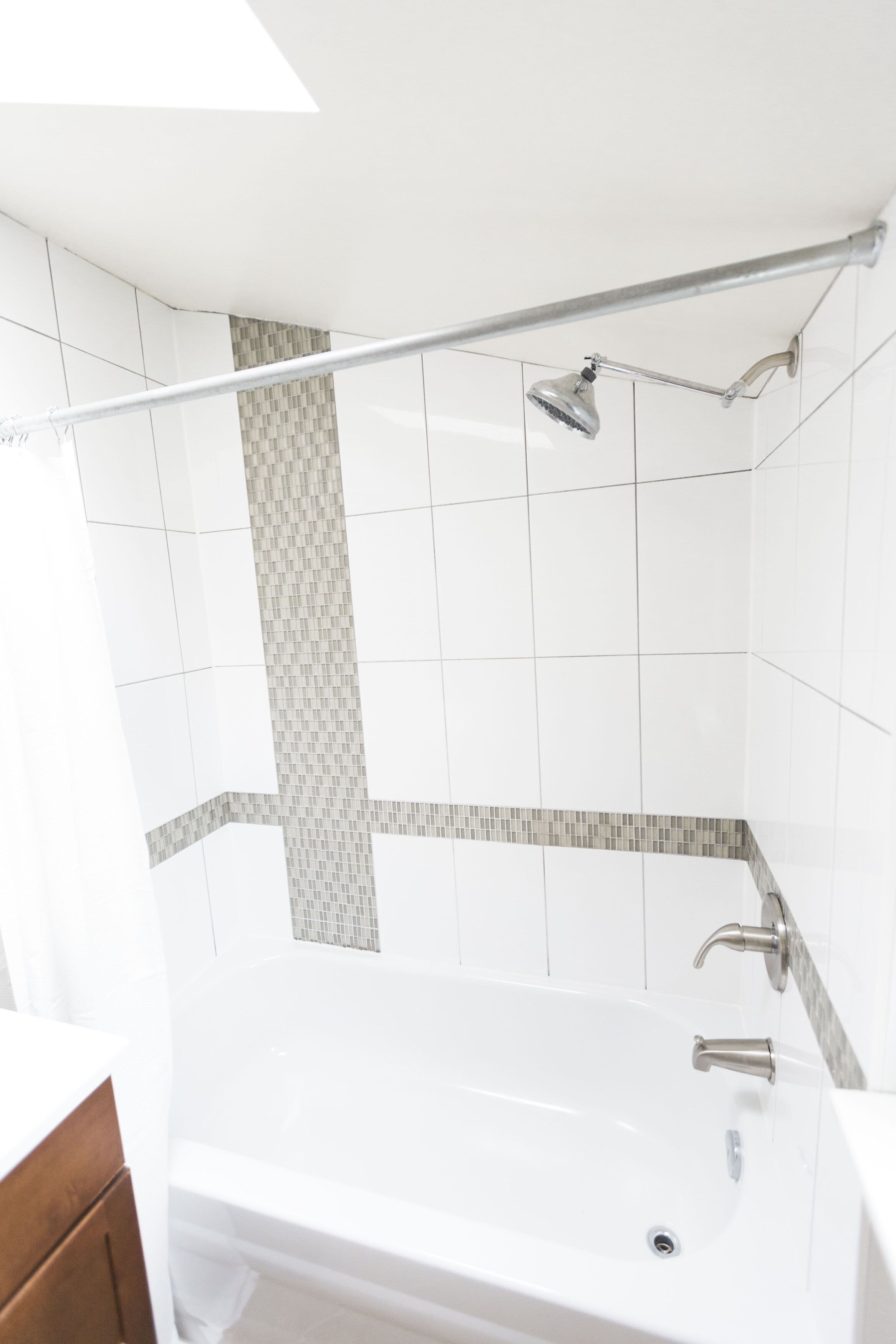 Un baño moderno con bañera, ducha y barra de apoyo.