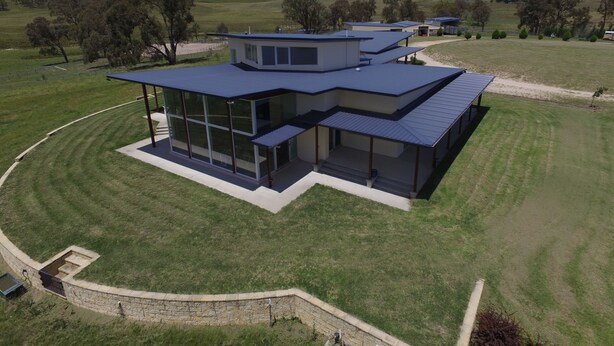 A modern house with a large glass facade, a flat roof, and a stone retaining wall. - Donegal Farmstay (Sandy Flat)