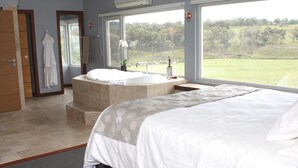 A bedroom with a large bed, a bathtub, and a view of a green landscape. - Donegal Farmstay (Sandy Flat)