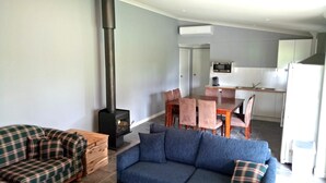 A modern living room with a sofa, a plaid sofa, a fireplace, and a dining area with chairs and a table. - Donegal Farmstay (Sandy Flat)