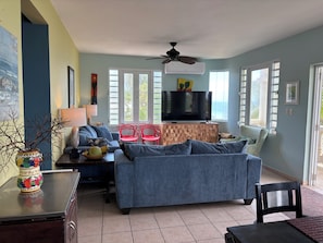 A living room with a sofa, TV, and red chairs.