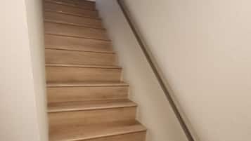 A wooden staircase with a handrail, leading to an upper floor.