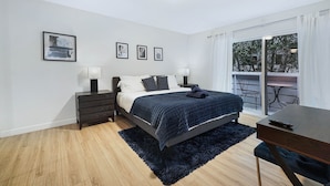 A modern bedroom with a bed, bedside tables, a desk, and a balcony with outdoor furniture. - Stylish Modern Home ★ Heart of Hollywood & Walkable ★ 2 Private Car Spots (Los Angeles)