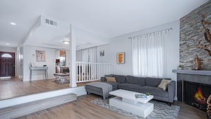 A modern living room with a grey sofa, white coffee table, and a fireplace. - Stylish Modern Home ★ Heart of Hollywood & Walkable ★ 2 Private Car Spots (Los Angeles)
