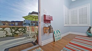A room with a wooden floor, a striped rug, a beach-themed sign, and a view of the outside. - A PERFECT BEACH COTTAGE  Exclusive Private Retreat - STEPS TO BEACH AND BAY (San Diego)