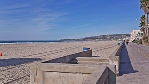 A beachside promenade with a concrete barrier, a clear sky, and a distant shoreline. - A PERFECT BEACH COTTAGE  Exclusive Private Retreat - STEPS TO BEACH AND BAY (San Diego)