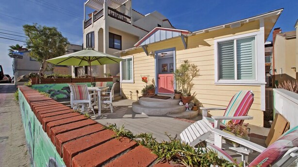 A two-story house with a patio area featuring outdoor furniture and potted plants. - A PERFECT BEACH COTTAGE  Exclusive Private Retreat - STEPS TO BEACH AND BAY (San Diego)
