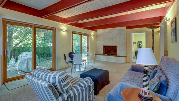 A spacious living room with a fireplace, a dining area with a table and chairs, and a large sliding glass door leading to an outdoor patio. - WALK EVERYWHERE!  SPACIOUS 4BR HOUSE, IN-TOWN REHOBOTH BEACH! PET-FREE. (Rehoboth Beach)