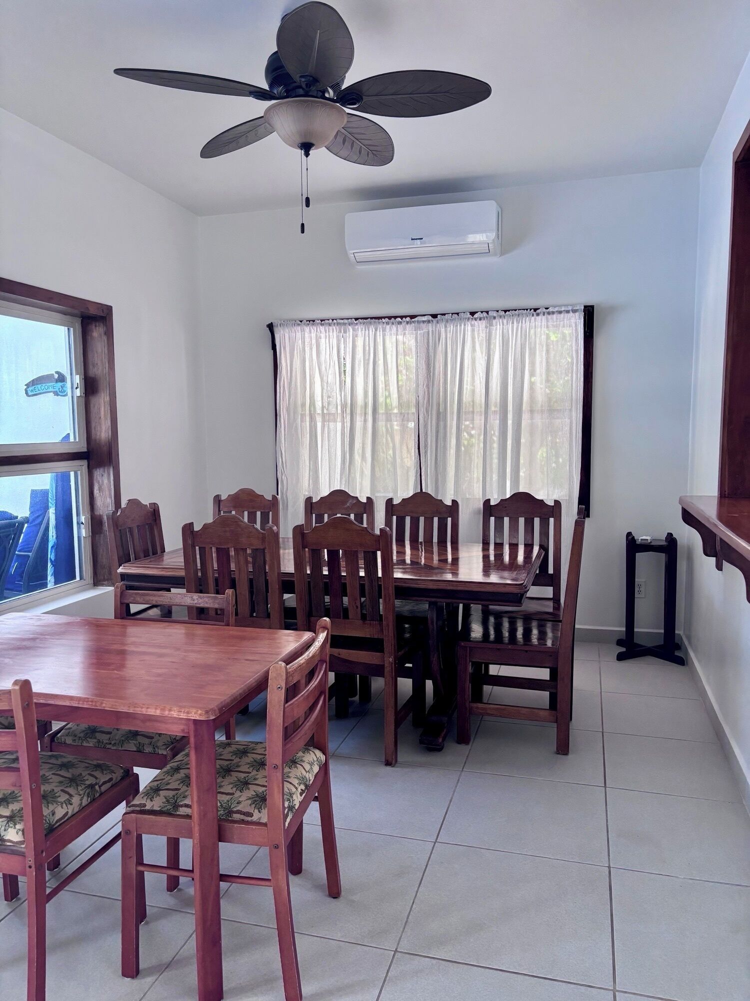 A dining area with a ceiling fan, a window with curtains, and a table with chairs.