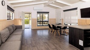 Un salon moderne comprenant un canapé, une table à manger, des chaises et un coin cuisine avec un comptoir et des appareils électroménagers.