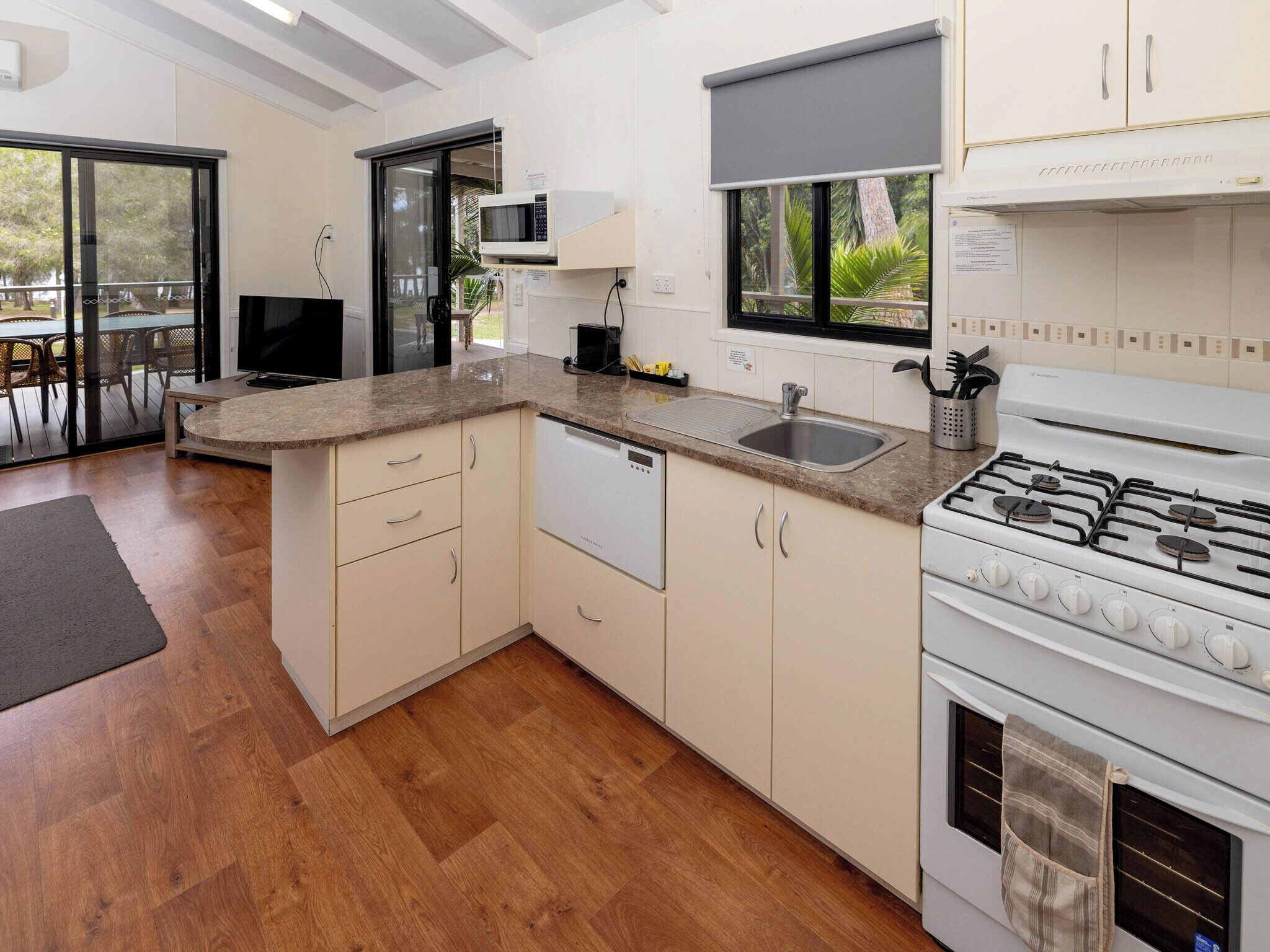 A modern kitchen with a built-in dishwasher, a gas stove, and a large window overlooking greenery.