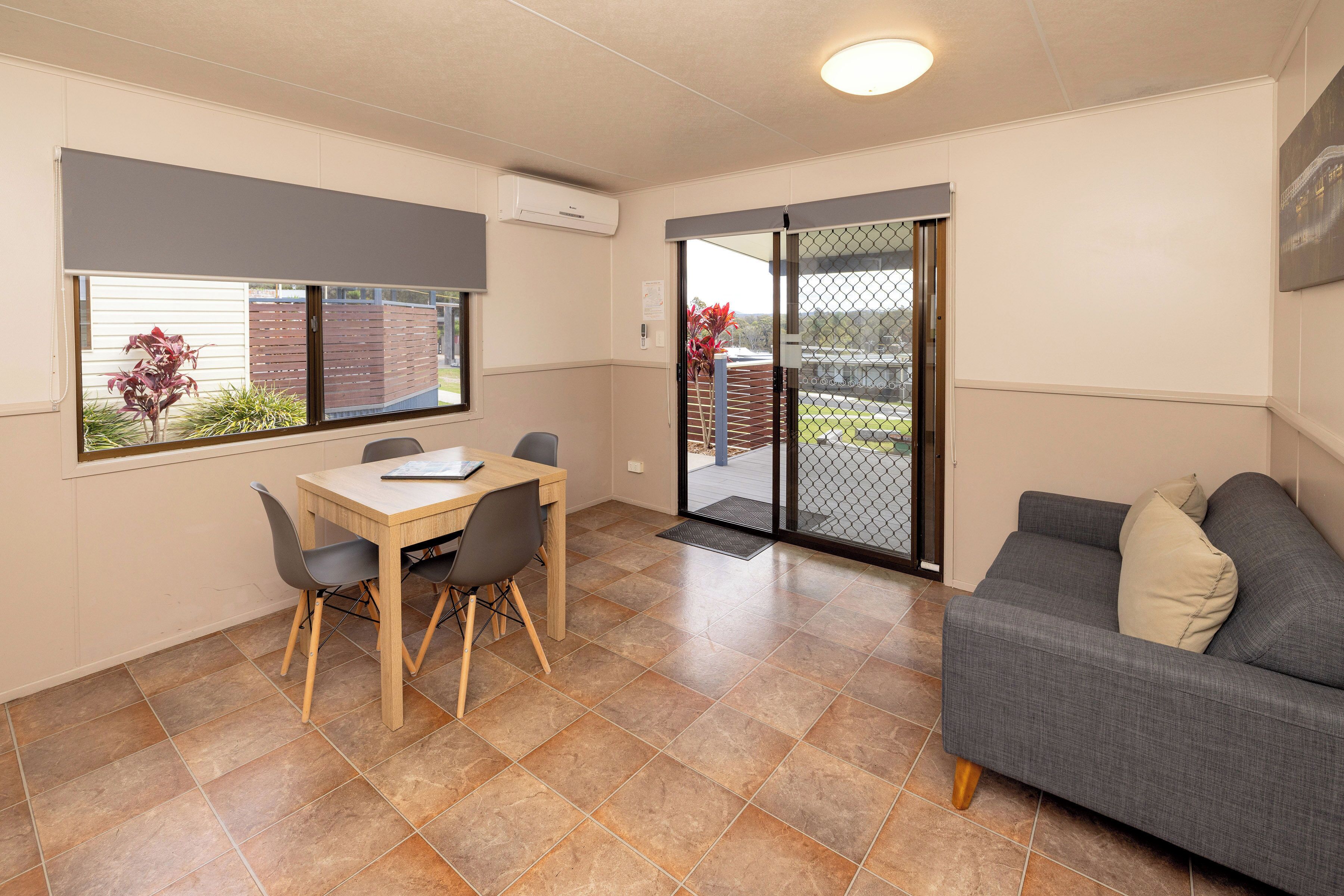 Un espace de vie compact comprenant un coin repas, un canapé et une porte-fenêtre coulissante donnant sur un balcon.