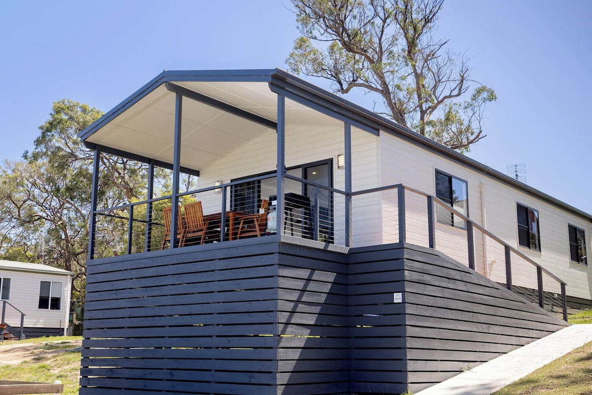 Een modern huis met een overdekte veranda, een klein terras en een trap naar de ingang.