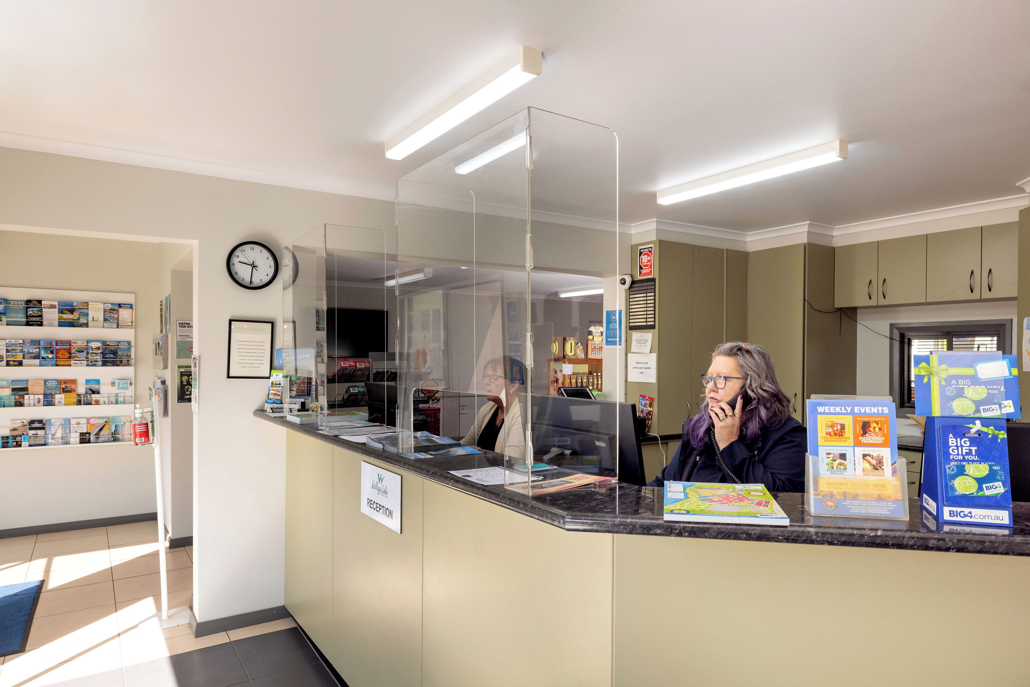 Un espace d’accueil avec un comptoir, une horloge et un panneau indiquant « RÉCEPTION ».