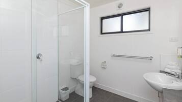 Un baño moderno con cabina de ducha de vidrio, inodoro, lavamanos y toallero.