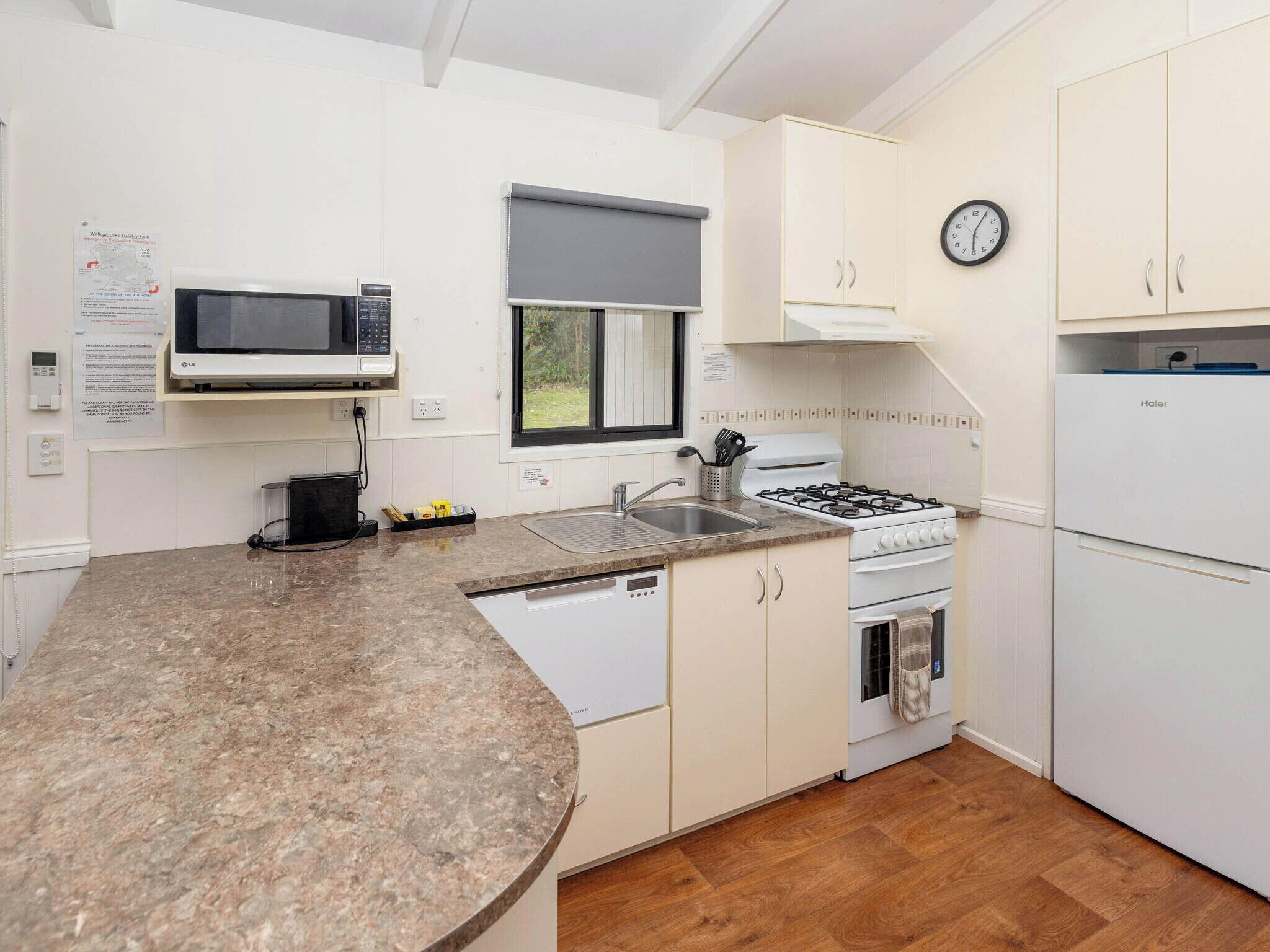 A modern kitchen with a granite countertop, white cabinetry, a microwave, a stove, and a refrigerator.