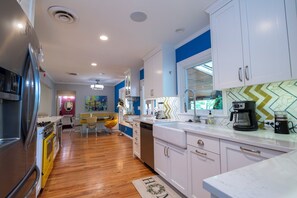 Una cocina moderna con armarios blancos, un refrigerador de acero inoxidable y piso de madera.