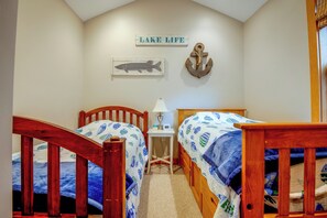 Une chambre à coucher avec deux lits en bois, une table de chevet, une lampe, une horloge murale et une pancarte sur laquelle on peut lire : « VIE AU BORD DU LAC ».