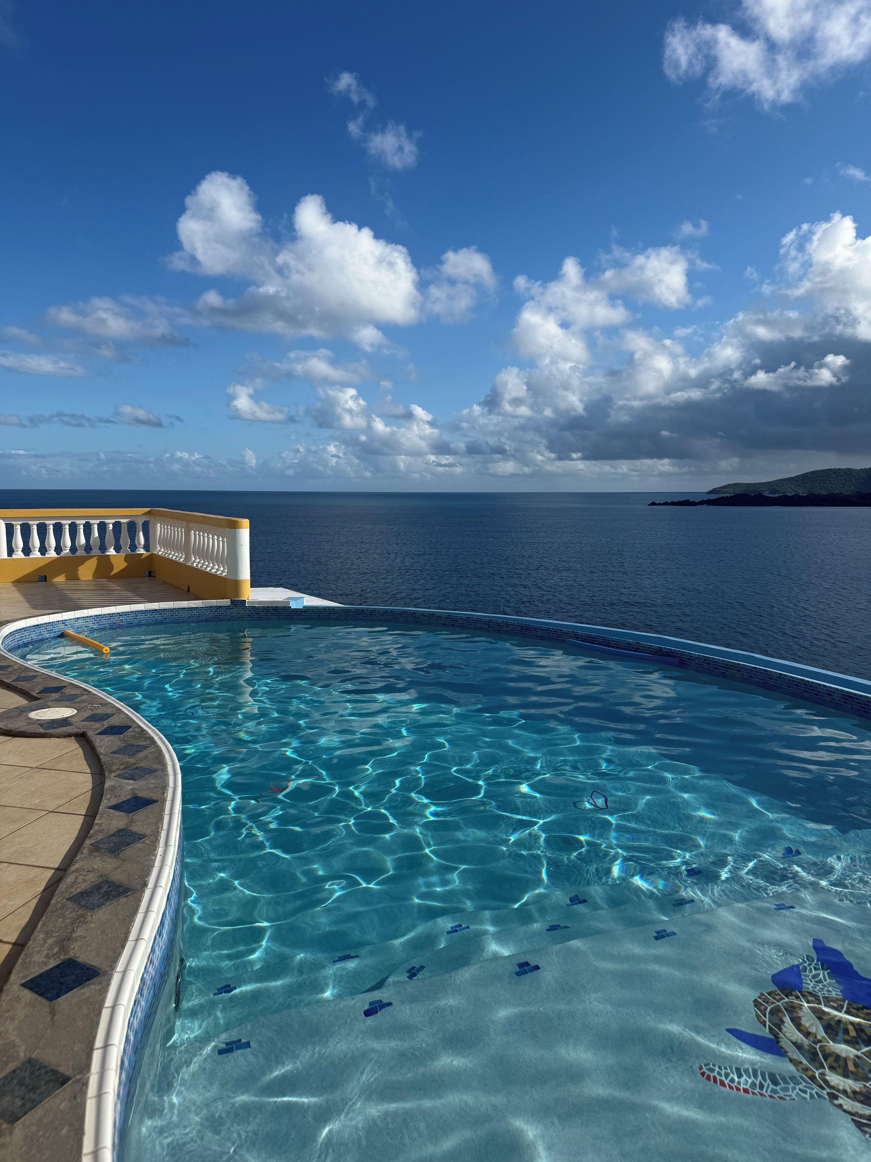 Piscina blava i nítida amb vistes al mar i una illa a la distància.