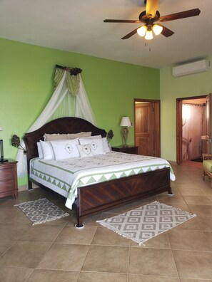 Un dormitorio con cama, mesita de noche, lámpara, ventilador de techo y puerta.