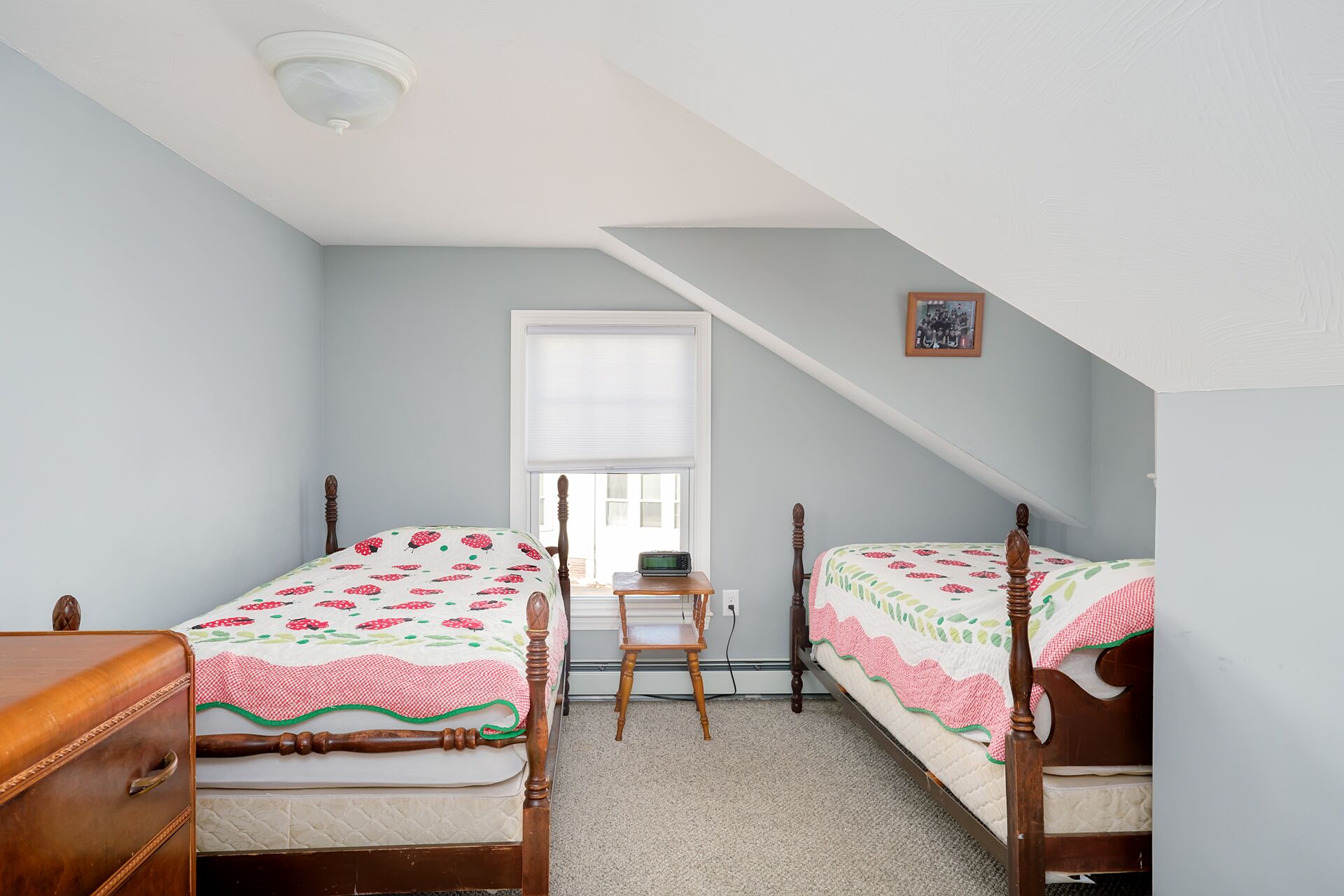 A bedroom with two wooden beds, a desk, and a chair.