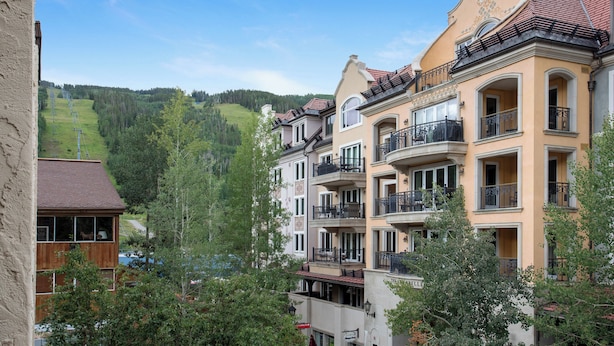 Ein mehrstöckiges Hotel mit Balkonen und Blick auf einen grünen Hügel.