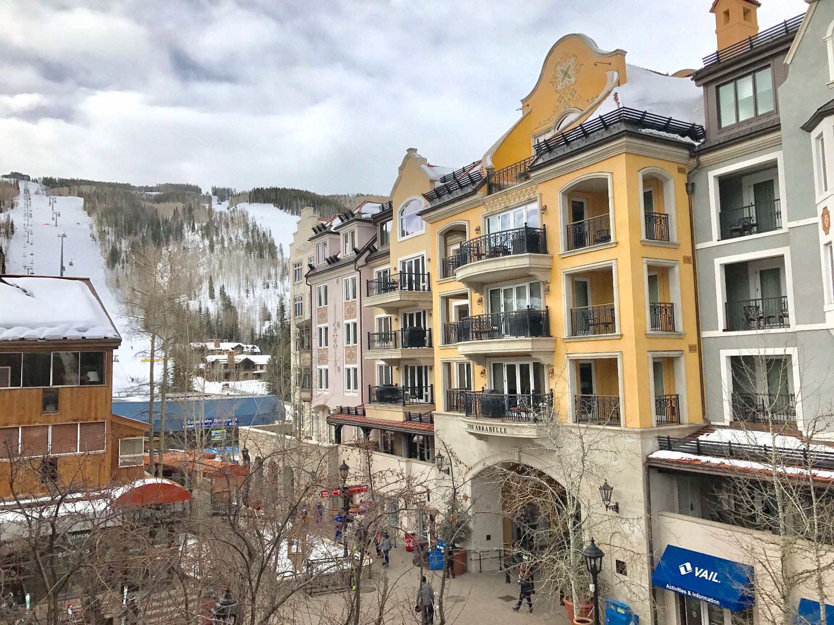 Um hotel com vários andares, varandas e vista para uma montanha coberta de neve.