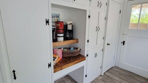 A room with white cabinets, a wooden shelf, and a coffee maker. - Beautiful hill country peace. (Blanco)