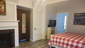 A bedroom with a checkered bedspread, a fireplace, a television, and a bookshelf. - Beautiful hill country peace. (Blanco)
