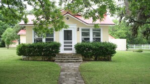 A house with a stone pathway leading to the front door, surrounded by well-maintained grass and hedges. - Beautiful hill country peace. (Blanco)