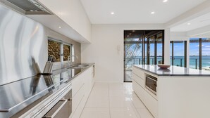 A modern kitchen with a large island, stainless steel appliances, and a view of the ocean.