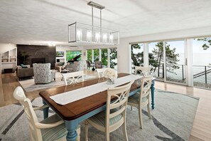Un espace de salle à manger moderne avec une table en bois, des chaises blanches et un lustre.